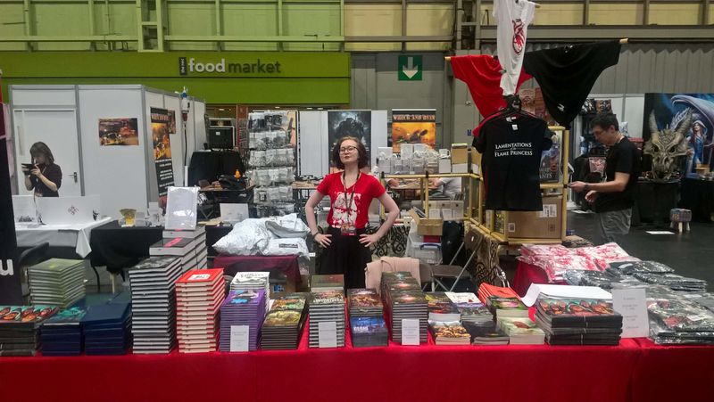 Woman behind convention stall with lots of books.