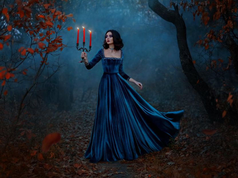 A young woman in a beautiful gown, holding a candelabra, wandering through a mystical forest.