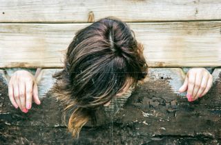 Close-up of woman locked in pillory, hanging her head